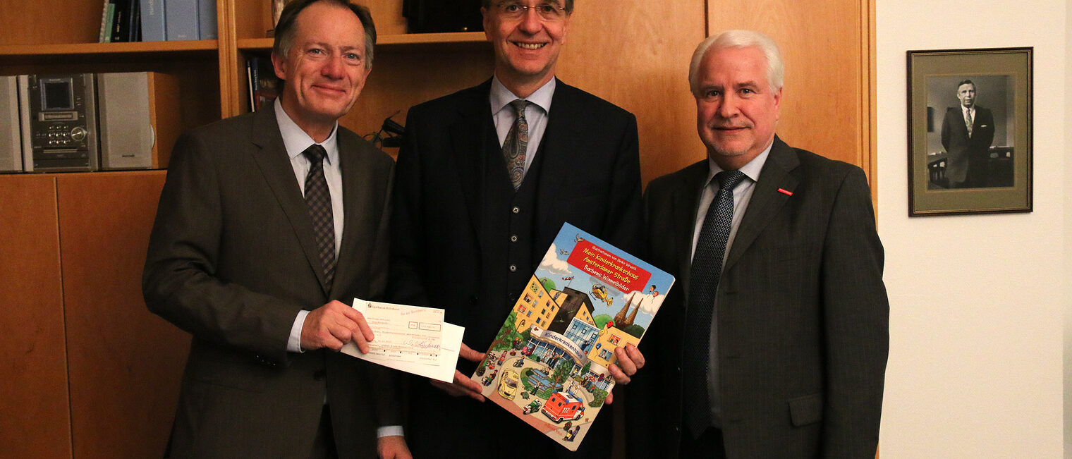 Hauptgeschäftsführer Dr. Ortwin Weltrich (l.) und Geschäftsführer Karl-Heinz Knoch (r.) überreichen Prof. Michael Weiß einen Spendenscheck fürs Kinderkrankenhaus