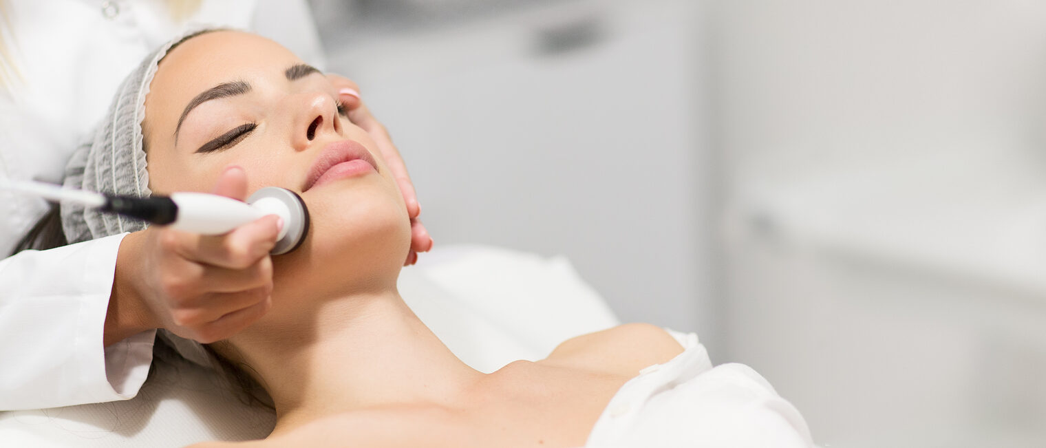 Beautiful young woman getting rejuvenating and tightening skin treatment at professional cosmetic salon. Schlagwort(e): aesthetic, rejuvenation, tightening, face, radiofrequency, laser, cavitation, massage, banner, copy, space, design, panoramic, header, ultrasound, endogeneous, tissues, body, fresh, skin, anti, aging, clinical, treatment, care, healthy, healthcare, clean, pigmentation, cosmetic, cosmetology, dermatology, device, electrolysis, glove, medical, procedure, regeneration, salon, therapy, beauty, beautiful, female, girl, woman, work, customer, professional, doctor, wellness, technology, hand, spa, lifting, aesthetic, rejuvenation, tightening, face, radiofrequency, laser, cavitation, massage, banner, copy, space, design, panoramic, header, ultrasound, endogeneous, tissues, body, fresh, skin, anti, aging, clinical, treatment, care, healthy, healthcare, clean, pigmentation, cosmetic, cosmetology, dermatology, device, electrolysis, glove, medical, procedure, regeneration, salon, therapy, beauty, beautiful, female, girl, woman, work, customer, professional, doctor, wellness