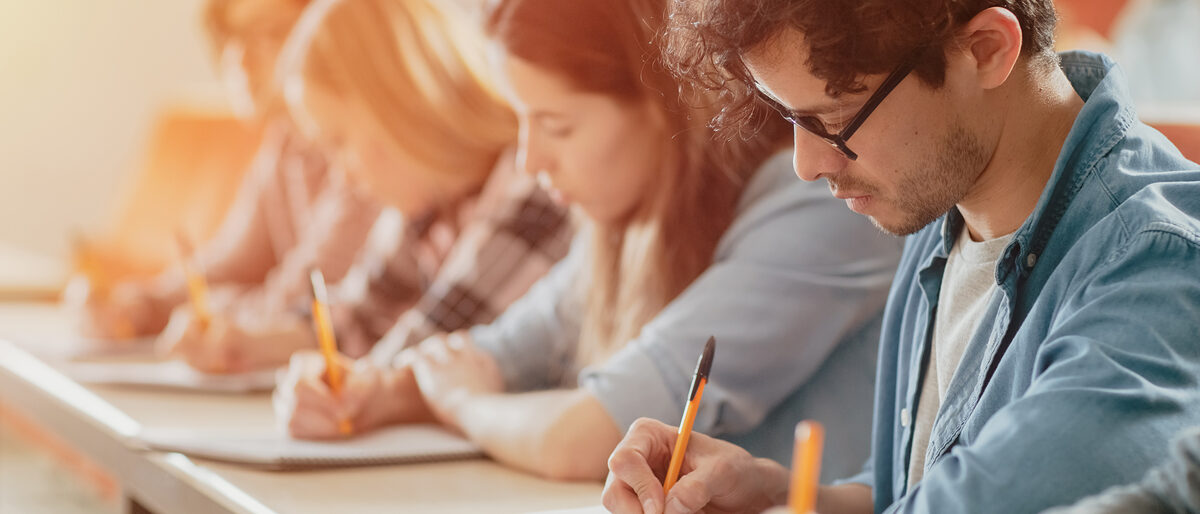 Moving Footage of a Row of Multi Ethnic Students in the Classroom Taking Exam/ Test. Focus on Holding Pens and Writing in Notebooks. Bright Young People Study at University. Schlagwort(e): Modern, academic, academy, adult, asian, auditorium, black, campus, caucasian, class, classroom, college, contemporary, course, desk, diversity, education, educational, exam, faculty, group, hispanic, indoors, institute, learning, lectern, lecture, lecture hall, lecturer, lesson, listening, mixed race, multi ethnic, notebook, notepad, pen, people, person, room, school, sitting, students, study, talking, teaching, test, university, woman, writing, young