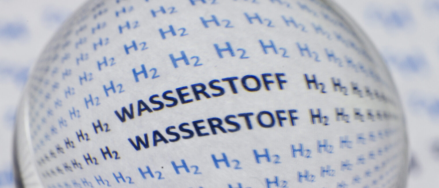 The words H2 and hydrogen in German written on a white surface under a magnifying glass Schlagwort(e): black, discovery, science, molecule, scientific, hydrogen, fuel,, black, discovery, science, molecule, scientific, hydrogen, fuel, physics, recharge, bio, atom, plastic, battery, optic, light, energy, background, spectacle, chemical, tree, african, death, shower, blue, man, element, torus, electron, metal, atomic, glasses, plant, sphere, fluid, research, fortune, study, symbol, space, conservation, magnifying, glass