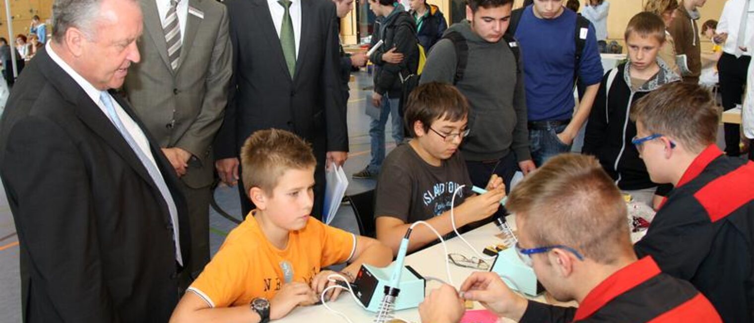 Oberbürgermeister Reinhard Buchhorn, Stefan Krause und Dr. Ortwin Weltrich (von links) beobachten Schüler der Theodor-Wuppermann-Schule beim Löten.