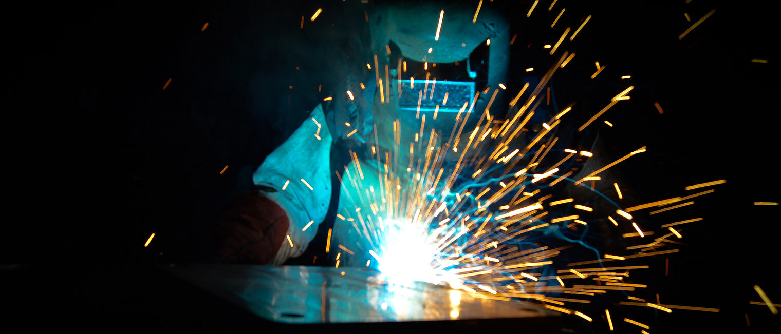 Welder uses torch to make sparks during manufacture of metal equipment, professional welding master Schlagwort(e): welder, weld, welded, welder mask, welding, welding torch, gas, workshop, torch, acetylene, alloy, arc, argon, blue, craft, craftsman, electric, engineering, electricity, electrode, fabrication, factory, fabricate, flame, fire, heat, helmet, hot, industrial, industry, iron, job, laborer, laboring, manufacturing, manufacture, mask, metal, metalwork, mig, production, protection, smoke, spark, tool, work, worker, workforce, working, workplace